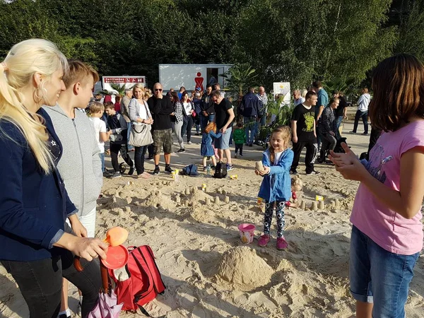 Ebeveynler ve kumla oynayan çocuklar