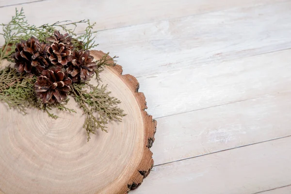 Wooden board with leaves of thuja and pine cones on wooden table — Stock Photo, Image