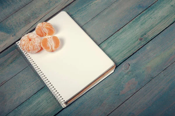 Řezy z mandarinky (mandarínština) s prázdnou notebook — Stock fotografie