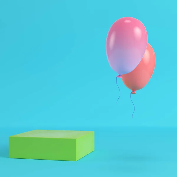Зелена коробка з двома літаючими повітряними кулями на яскраво-синьому фоні в — стокове фото
