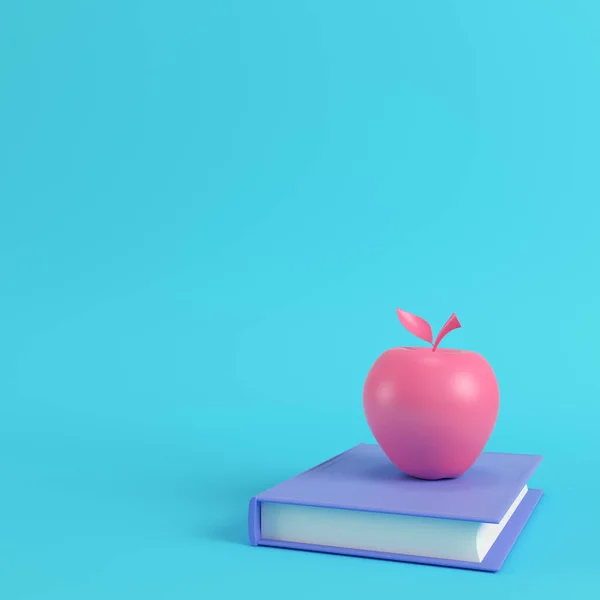 Roze apple aan een boek over de heldere blauwe achtergrond in pastel kleuren — Stockfoto