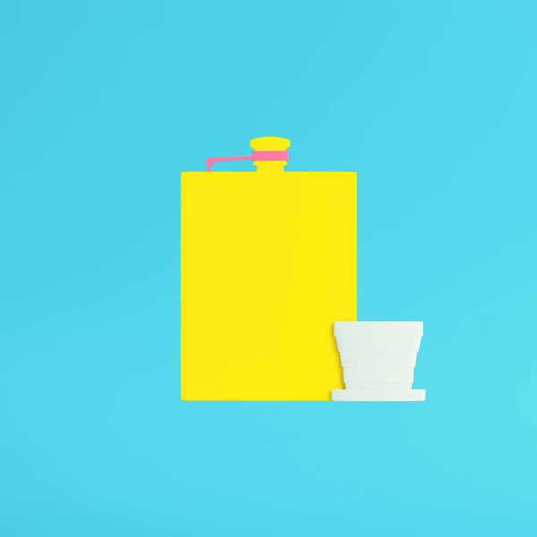 Yellow hip flask with cup on bright blue background in pastel co — Stock Photo, Image