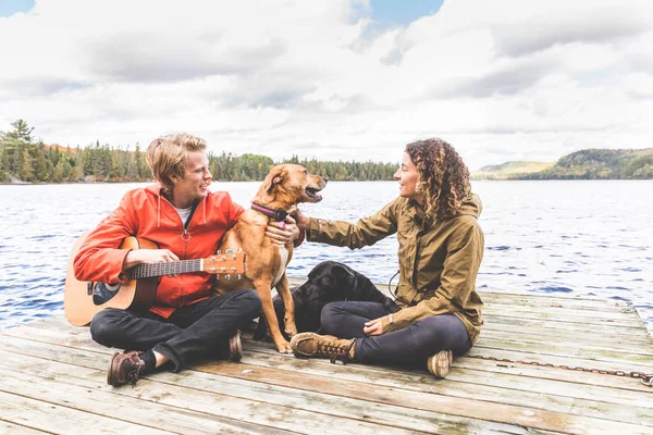 Glückliches Paar spielt mit Hund auf der Anklagebank — Stockfoto