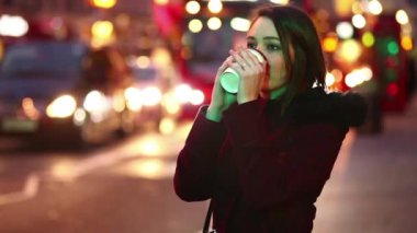 Woman standing by a busy road at night