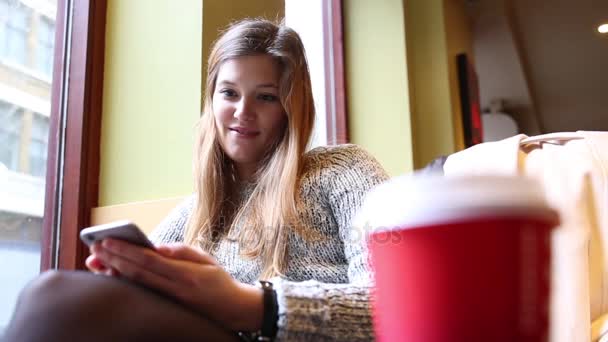 Женщина в кафе пишет смс по телефону — стоковое видео