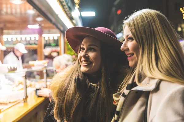 Två unga kvinnor att köpa mat på Julmarknad i München — Stockfoto