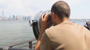 new York'ta dürbün ile bakan genç adam
