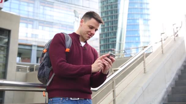 Jonge man te typen op de telefoon in de stad — Stockvideo