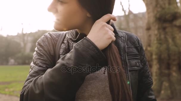 Chica haciendo una trenza con pelo en el parque. Movimiento lento — Vídeo de stock