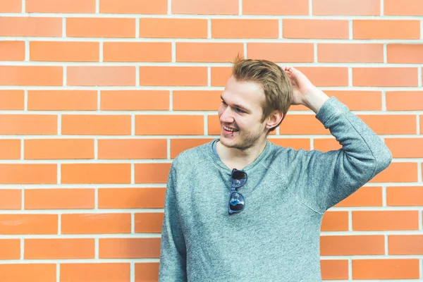 Portret van de jonge man tegen een bakstenen muur — Stockfoto