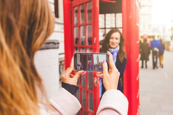 Des amis prennent une photo dans une cabine téléphonique de Londres — Photo