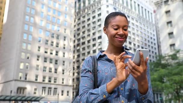 Чорна жінка друкує по телефону в місті — стокове відео