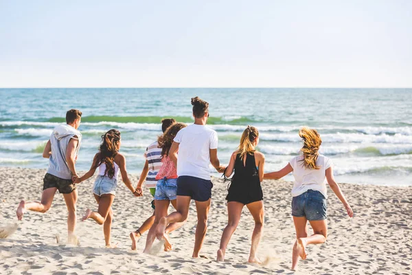 Gruppo multirazziale di amici che corrono sulla spiaggia — Foto Stock