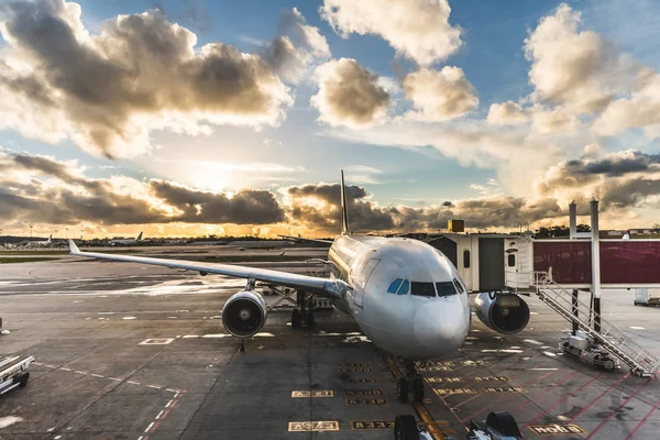 Passageiros de embarque de avião no aeroporto ao pôr do sol — Fotografia de Stock