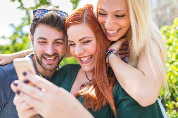 Groep vrienden met smartphone samen plezier in het park — Stockfoto