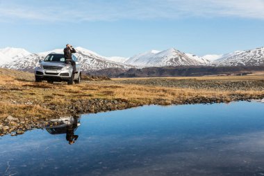 Man explorer in Iceland sitting on the car clipart