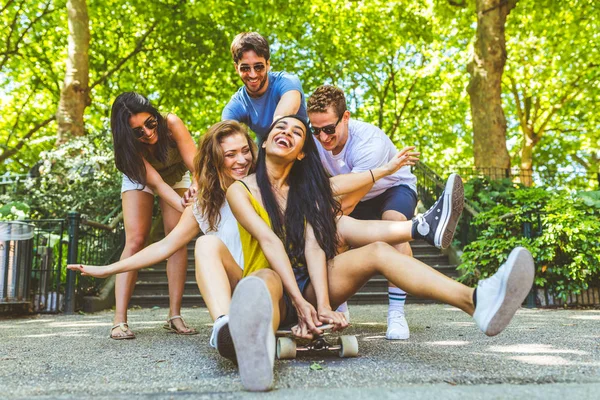 Grupa przyjaciół, zabawy z deskorolka w parku — Zdjęcie stockowe