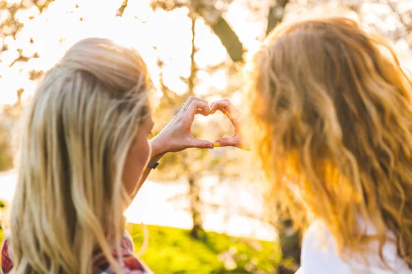 Lésbicas casal, coração em forma de mãos no parque, símbolo do amor — Fotografia de Stock