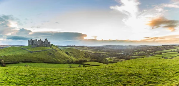 Panorama do campo com castelo arruinado em uma colina ao pôr do sol — Fotografia de Stock