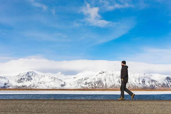 Férfi sétált a közúti, a hó és a hegyek a háttérben — Stock Fotó