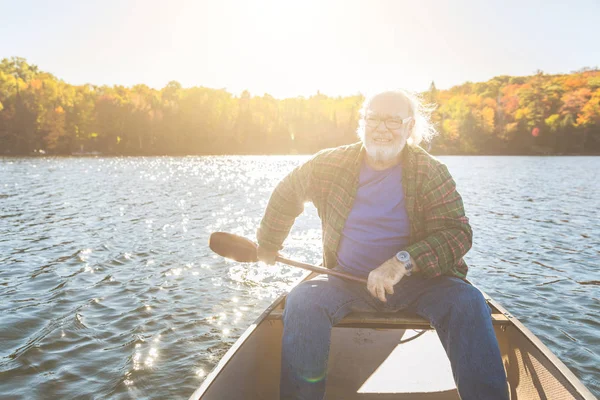 Senior man met kano Roeien op een zonnige dag — Stockfoto