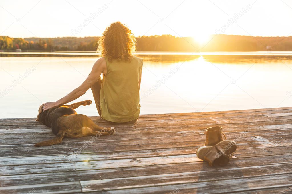 Woman and dog relaxing on the dock at sunset