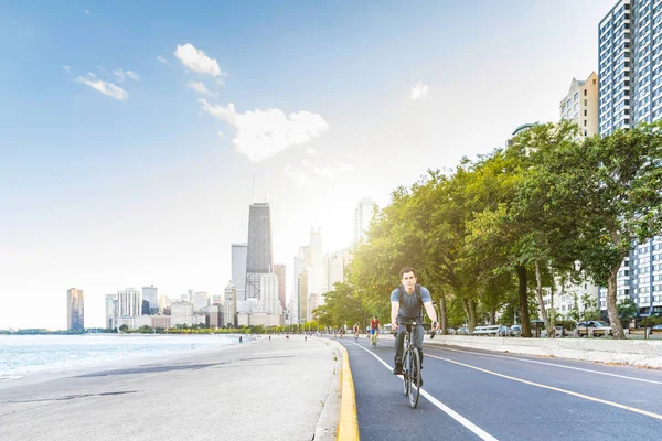 Hombre ciclismo en Chicago con la ciudad en el fondo — Foto de Stock