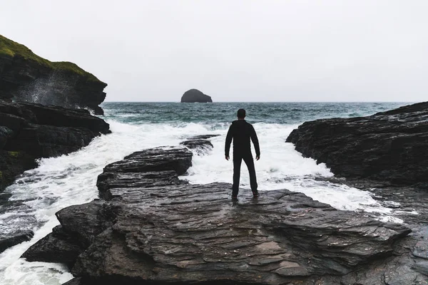 Homem de frente para o oceano e ondas durante uma tempestade — Fotografia de Stock