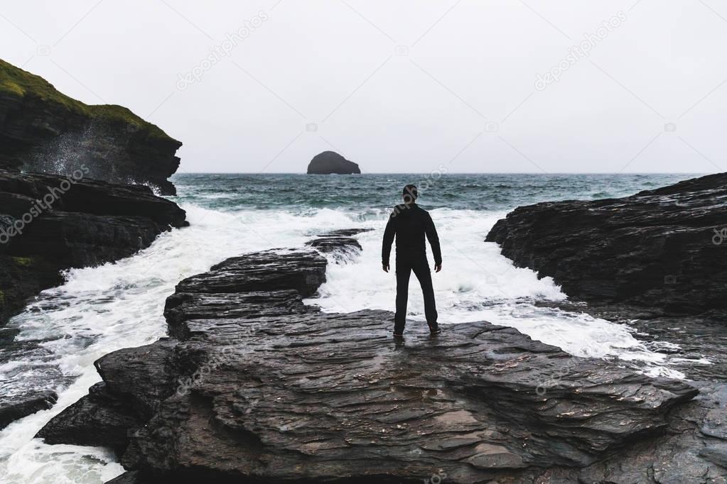 Man facing ocean and waves during a storm