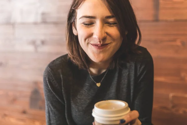 Молодая женщина пьет кофе и делает смешное лицо — стоковое фото