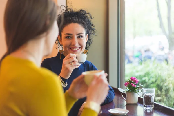 Två kvinnor på ett café leende och dricker kaffe tillsammans — Stockfoto