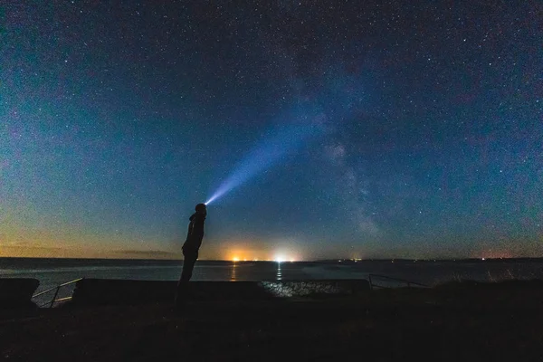 Muž s světlometů zíral na noční obloze — Stock fotografie
