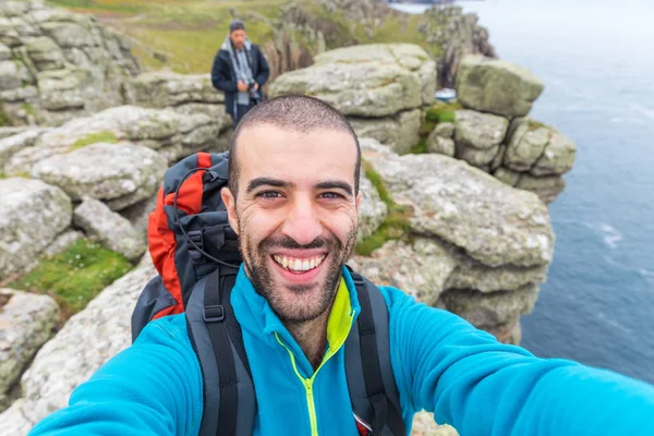 Adam yürüyüş yapıyor ve uçurumların tepesinde selfie çekiyor. — Stok fotoğraf