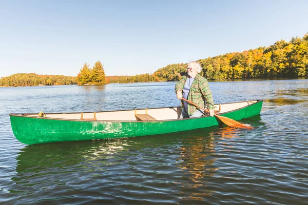 Uomo con canoa al lago in una giornata di sole autunnale — Foto Stock