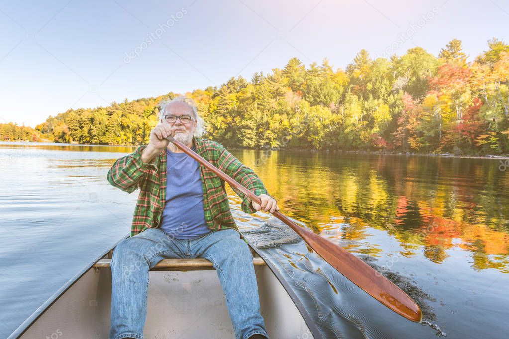 Man with canoe at lake on a sunny autumn day