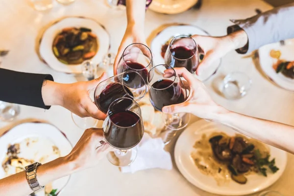 Pessoas brindam com vinho tinto no restaurante — Fotografia de Stock