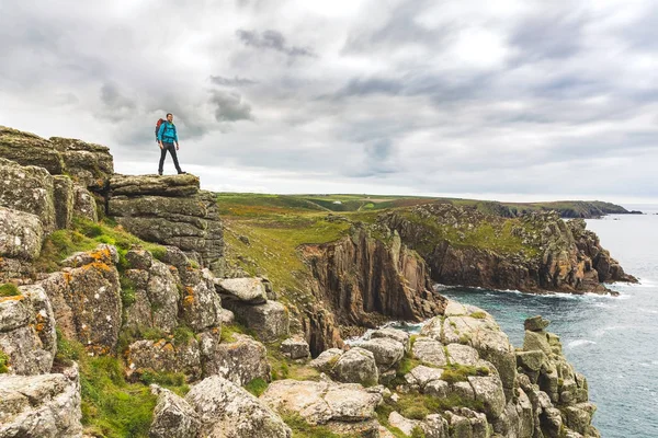 Uomo in piedi su una scogliera rocciosa godendo la vista — Foto Stock