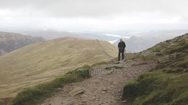 Чоловік ходить по гірській стежці в похмурий день — стокове відео