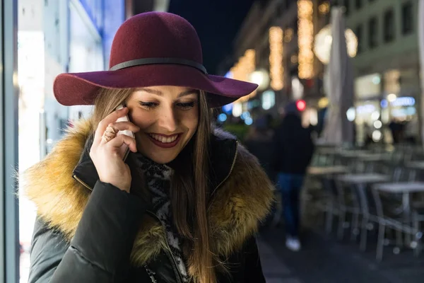 Woman wearing hat talking on the phone at night — Stock Photo, Image