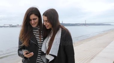 Lizbon nehir kenarında bir smartphone ile iki kadın