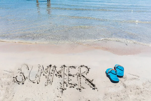 Escritura de verano en la arena junto al mar con chanclas —  Fotos de Stock