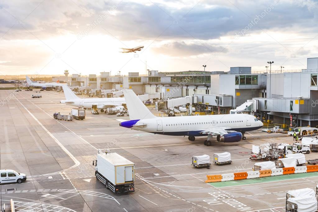 Busy airport view with airplanes and service vehicles at sunset