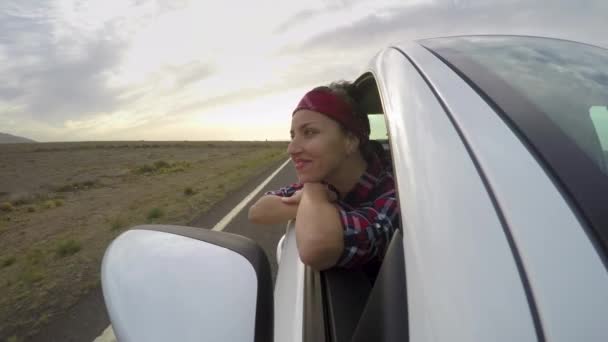 旅行を楽しんでいる車の窓から美しい女性 若い女性が楽しみながら移動車の彼女の頭を維持します ボンネット 放浪癖の概念からの眺め — ストック動画