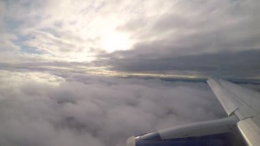 Bulutların arasından gün batımında, kanat görünümü üzerinde uçan uçak