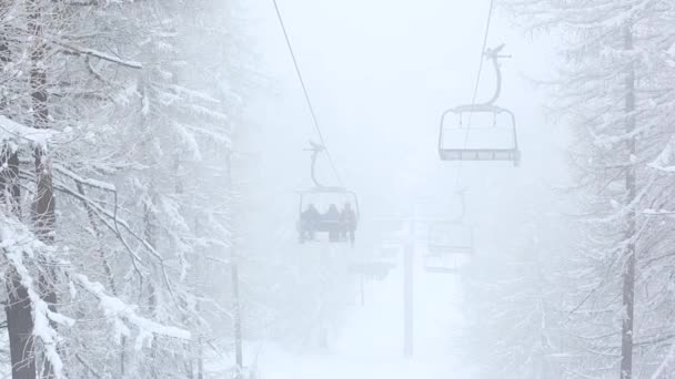 Wyciąg krzesełkowy między drzewami, mgły i śniegu w górach — Wideo stockowe