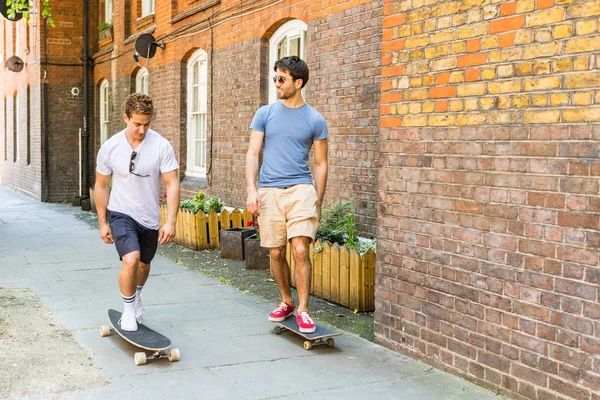 Dos hombres que van en monopatín por el pavimento en Londres — Foto de Stock