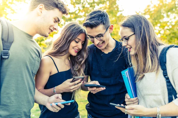 Groupe d'amis adolescents avec smartphones au parc — Photo