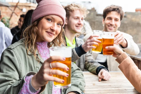 Amigos bebendo e brindando com cerveja no pub — Fotografia de Stock