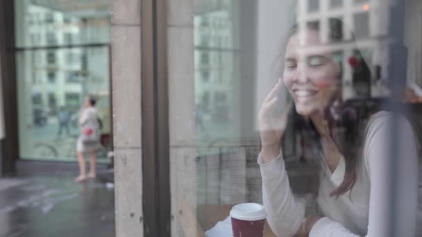 Ung kvinna i ett café njuter av en kaffe och använda en smartphone - Beautiful br — Stockvideo