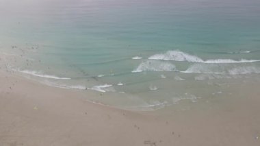 Deniz kenarındaki dalgalar ve plajlar. Yaz mevsiminde sörf yapan insanlar.